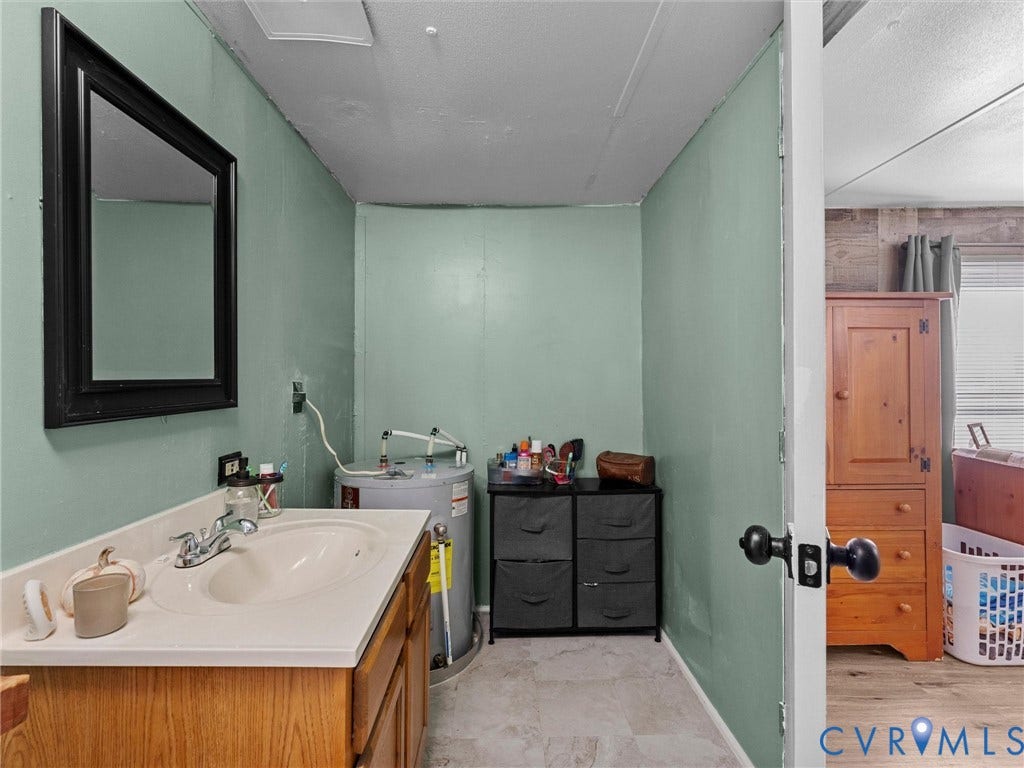 17009 Lansmill Drive, South Chesterfield, VA 23834 Recessed sink basin with a chrome faucet, wood-finish vanity, and wall-mounted mirror