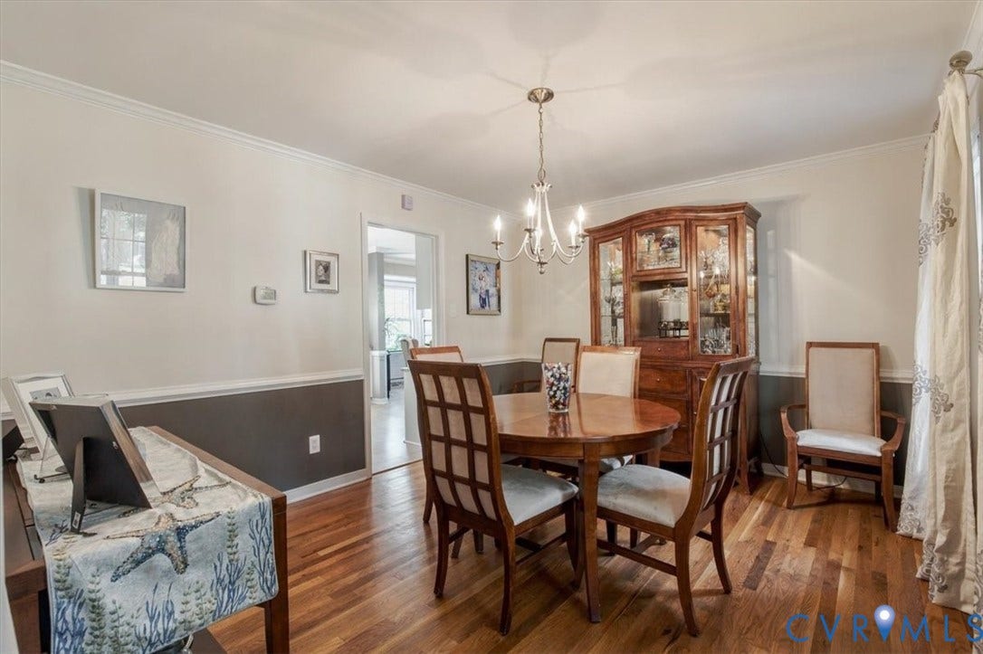863 Watch Hill Road, Midlothian, VA 23114 Elegant dining room showcasing rich wood-finish flooring, a formal dining table with lattice-back chairs, and a substantial wood cabinet with glass-front display shelving