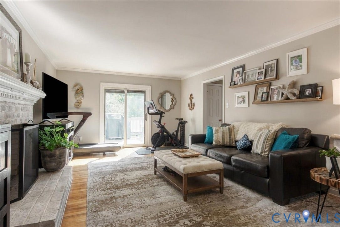 863 Watch Hill Road, Midlothian, VA 23114 Bright, open living room showcasing hardwood-finish flooring, a wood-burning fireplace with white surround and mantel, and French doors with transom windows providing natural light