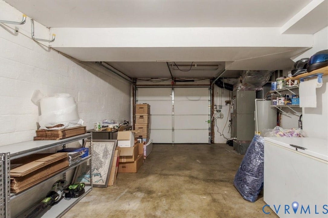 863 Watch Hill Road, Midlothian, VA 23114 Garage space featuring a roll-up garage door, painted cinder block walls, and exposed ceiling beams