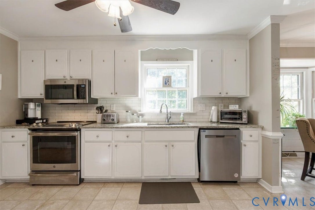 863 Watch Hill Road, Midlothian, VA 23114 Bright, open kitchen featuring white cabinetry, stainless steel appliances including a built-in microwave and dishwasher, tile countertops, a large window above the sink, and tile flooring throughout