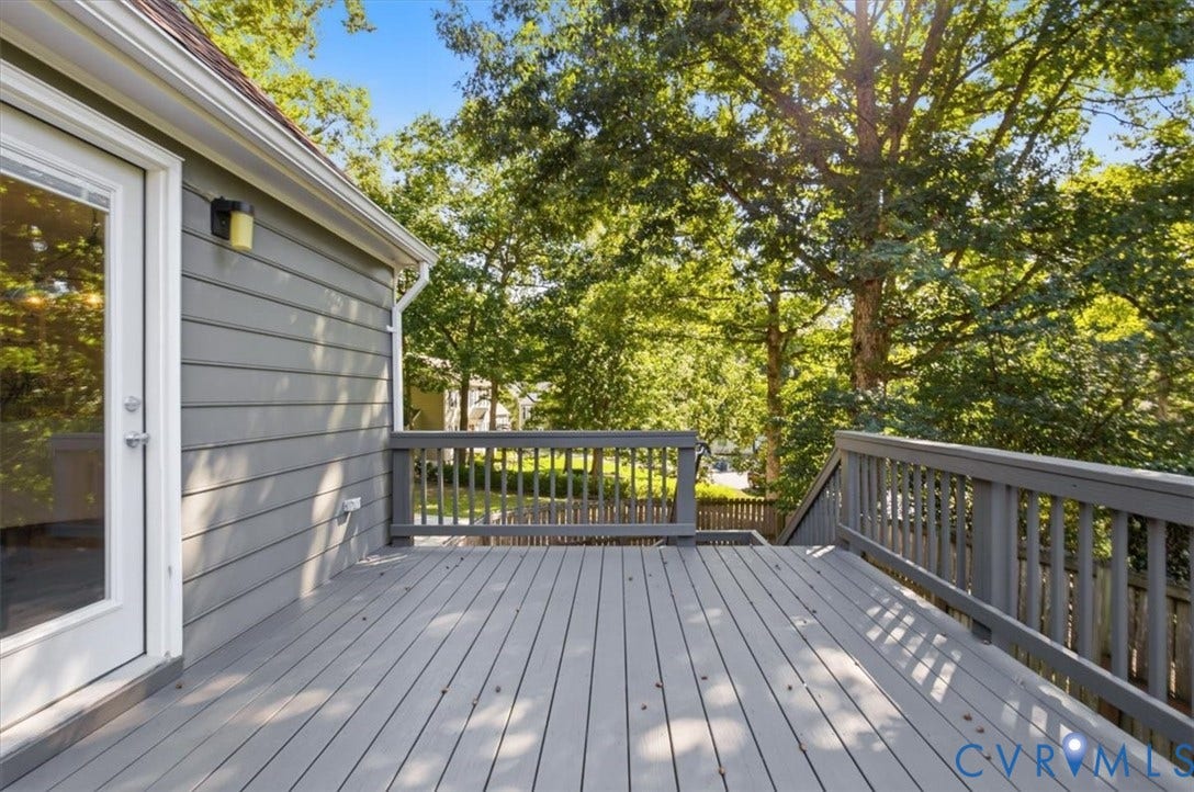 863 Watch Hill Road, Midlothian, VA 23114 Spacious outdoor deck with gray wood-finish decking and railing, featuring a glass-paned door, exterior wall lighting, and natural tree surroundings