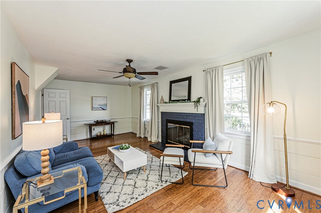1608 Lochwood Drive, Henrico, VA 23238 Bright living room showcasing hardwood flooring, a wood-burning fireplace with blue tile surround, ceiling fan, and abundant natural light from multiple windows