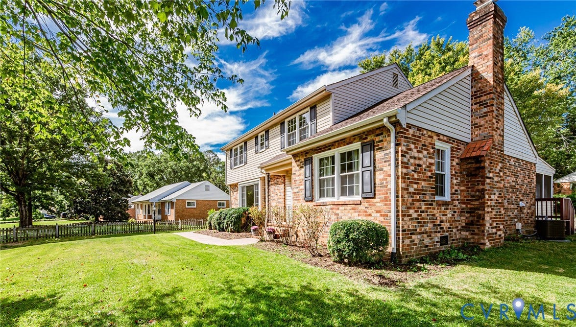1608 Lochwood Drive, Henrico, VA 23238 Brick exterior with white siding accents, multi-pane windows with dark shutters, prominent brick chimney, and a sprawling front lawn