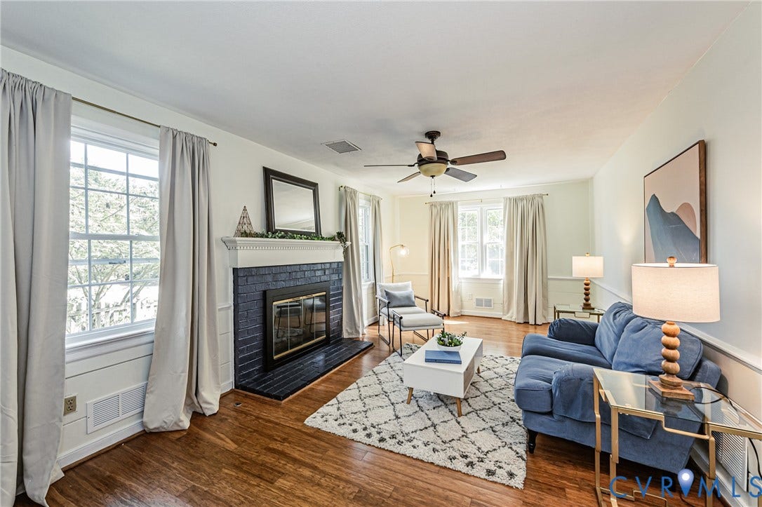 1608 Lochwood Drive, Henrico, VA 23238 Living area featuring hardwood flooring, a fireplace with a black brick surround and white mantel, multiple large windows, a ceiling fan, and white walls with chair rail molding