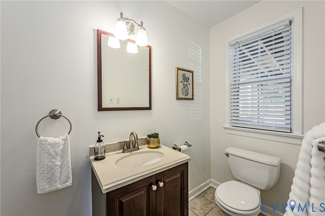 1608 Lochwood Drive, Henrico, VA 23238 Vanity with an integrated sink and base cabinetry, complemented by a wall-mounted mirror and sconce lighting