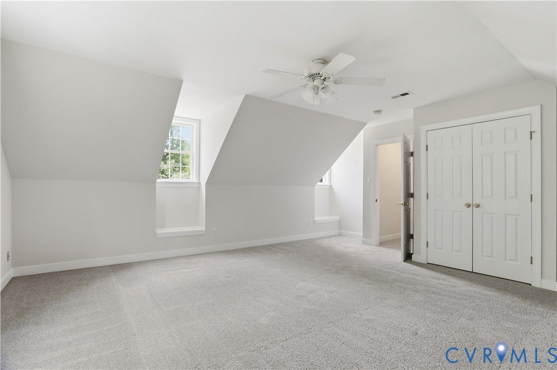 10721 Sheppards Way Drive, Sheppards Way, Glen Allen, VA 23060 Spacious upper-level bedroom featuring soaring vaulted ceilings, abundant natural light from a dormer window, neutral carpet flooring, a ceiling fan with integrated lighting, and dual closets with white six-panel doors
