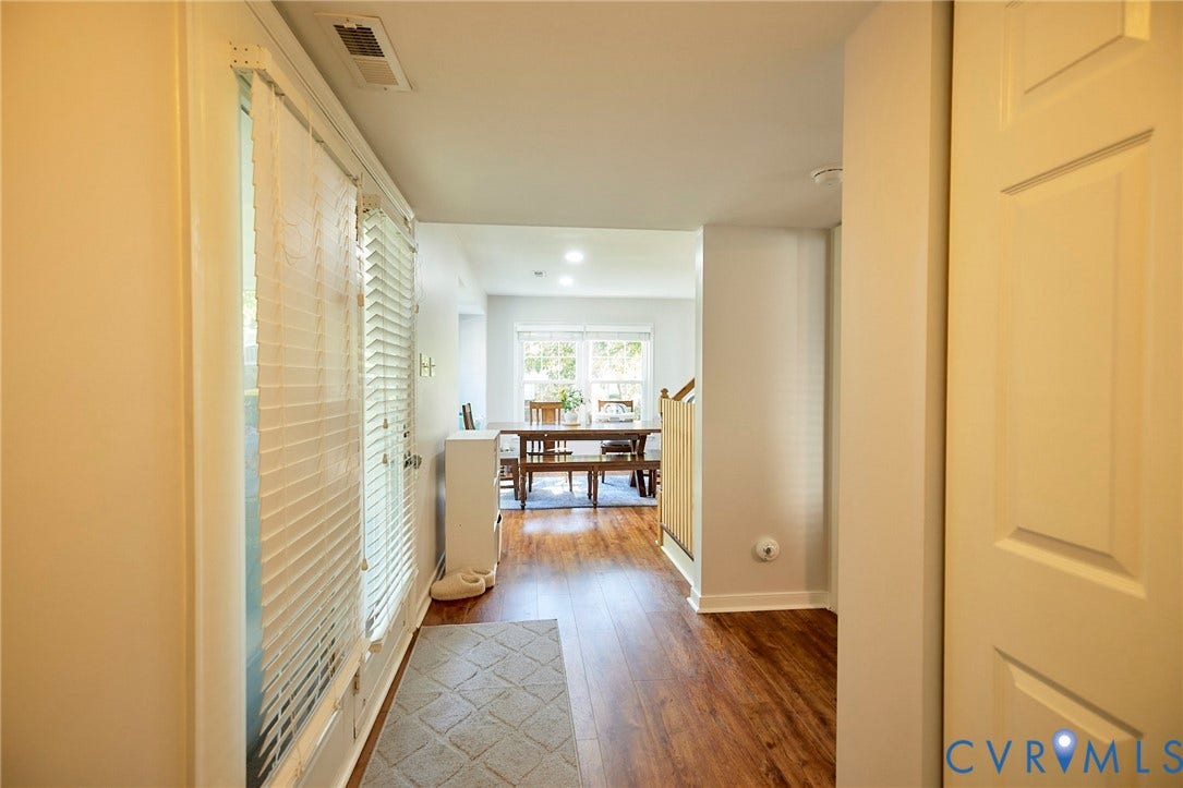 2633 Bradway Lane, Henrico, VA 23233 Bright hallway featuring warm yellow-painted walls, gleaming wood-finish flooring, and multiple six-panel doors providing access to adjoining spaces