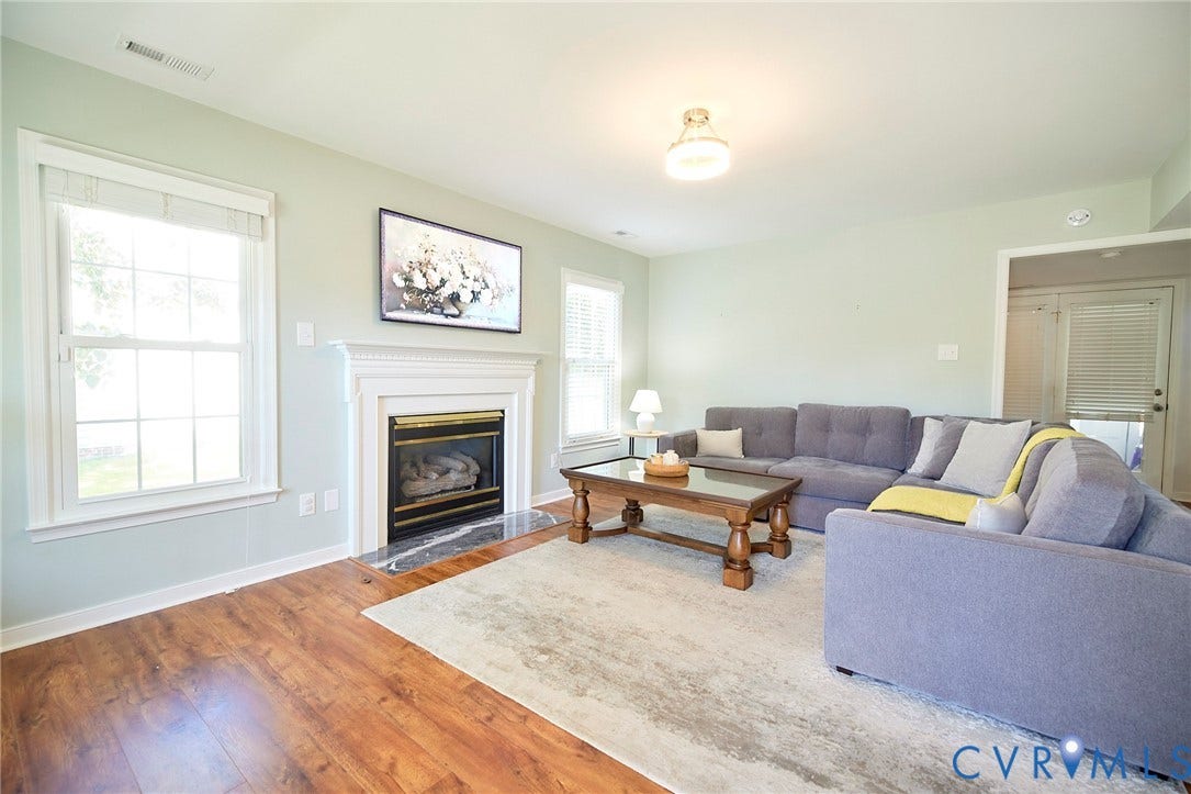 2633 Bradway Lane, Henrico, VA 23233 Spacious living room featuring hardwood flooring, a gas fireplace with built-in surround, large windows with natural light, and neutral wall finishes