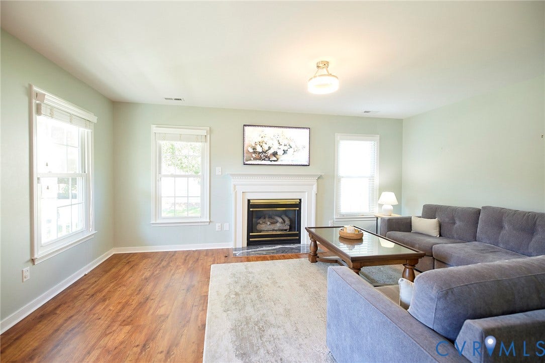 2633 Bradway Lane, Henrico, VA 23233 Bright and airy living room featuring hardwood flooring, soft sage-green walls, and abundant natural light from multiple windows