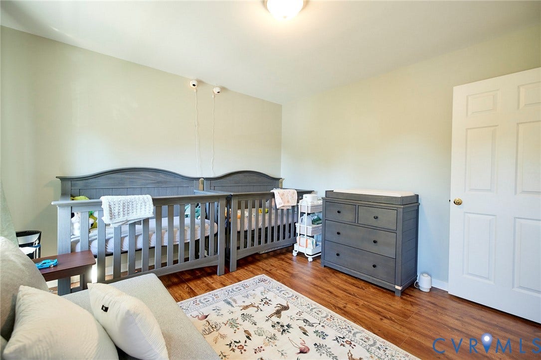 2633 Bradway Lane, Henrico, VA 23233 Spacious nursery featuring hardwood flooring, two full-size cribs with coordinating bedding, a multi-drawer dresser with ample storage, and abundant natural light from recessed ceiling fixtures