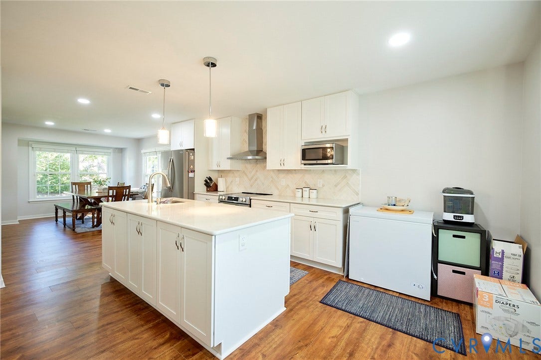 2633 Bradway Lane, Henrico, VA 23233 Kitchen featuring a large center island with pendant lighting, wood-finish flooring, white cabinetry, stainless steel appliances, and a tiled backsplash
