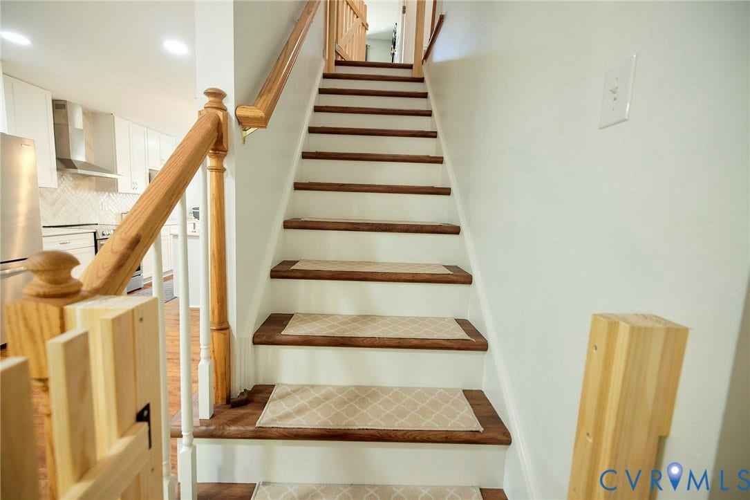 2633 Bradway Lane, Henrico, VA 23233 Hardwood stair treads with a wood-finish handrail, white risers, and patterned stair runners