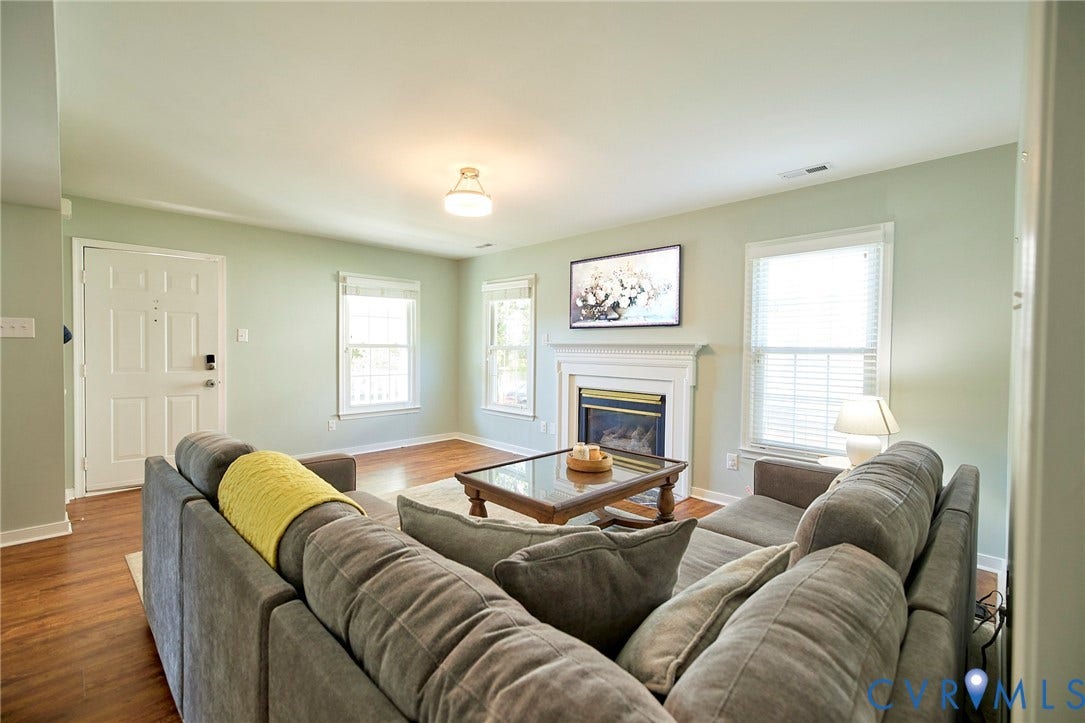 2633 Bradway Lane, Henrico, VA 23233 Spacious living room featuring hardwood flooring, a gas fireplace with surround mantel, recessed ceiling lighting, and large windows providing natural light throughout