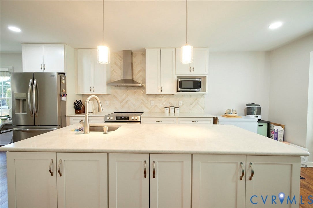 2633 Bradway Lane, Henrico, VA 23233 Kitchen featuring an expansive island with an undermount sink, pendant lighting, stainless steel appliances, and a herringbone tile backsplash