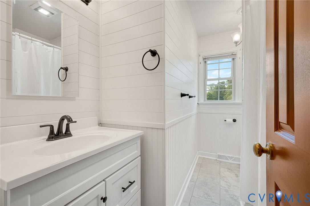 7516 Oakmont Drive, Henrico, VA 23228 White vanity with integrated sink, black-finish faucet, shiplap and wainscoting paneling, and tile flooring