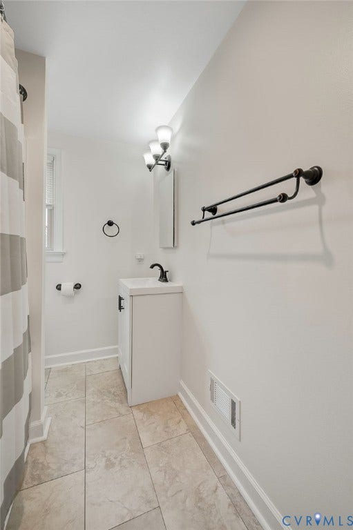 7516 Oakmont Drive, Henrico, VA 23228 White single vanity with black hardware, complementing black wall-mounted light fixture, and large format floor tiling
