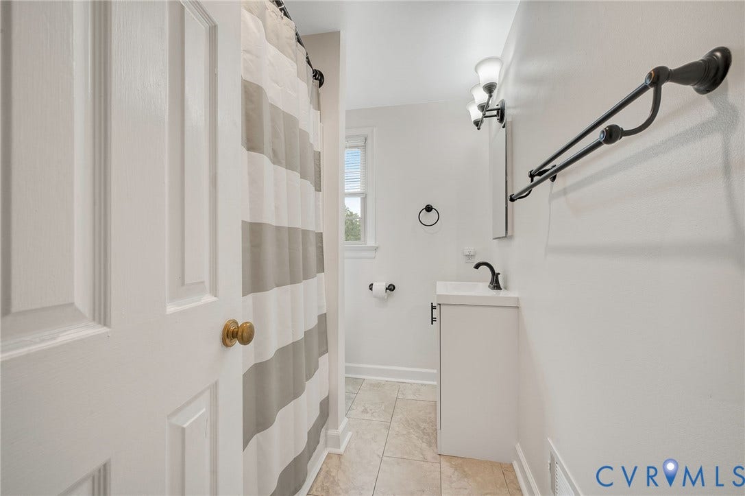 7516 Oakmont Drive, Henrico, VA 23228 White vanity with integrated sink, black hardware, wall-mounted lighting, and neutral floor tile