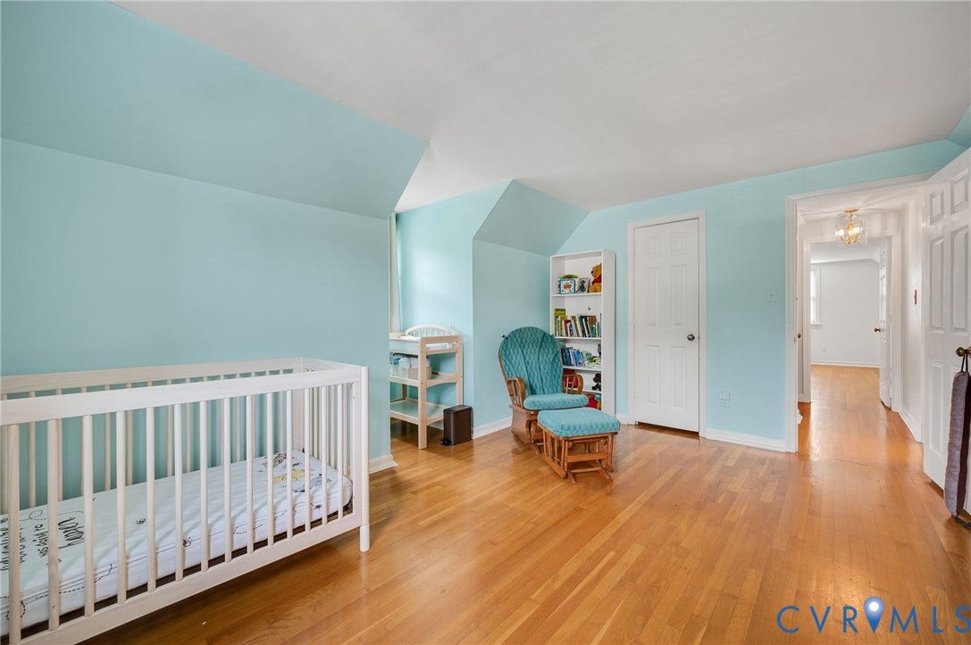 7516 Oakmont Drive, Henrico, VA 23228 Bright nursery featuring soft blue walls, white crib, warm wood-finish flooring, and ample natural light from multiple windows