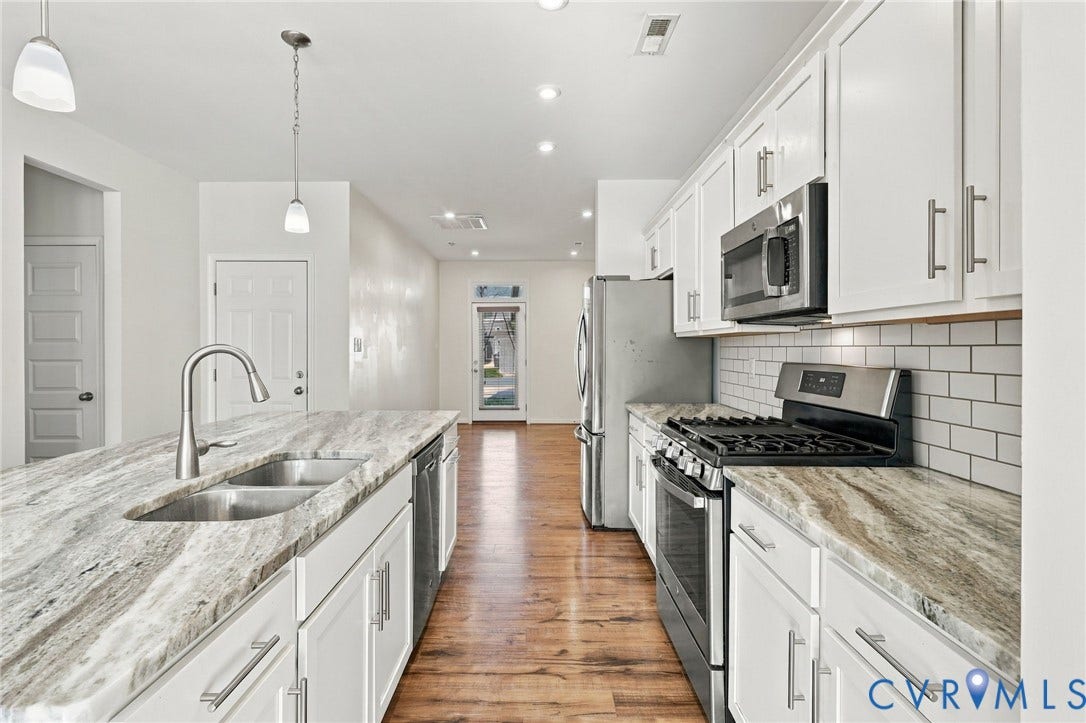 10818 Ashton Poole Place, Henrico, VA 23059 Kitchen featuring white shaker-style cabinetry, stainless steel appliances, a subway tile backsplash, light-toned countertops, and wood-finish flooring