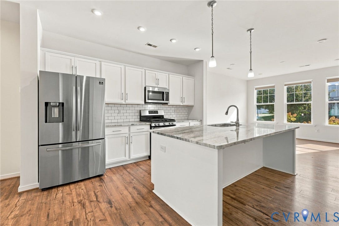 10818 Ashton Poole Place, Henrico, VA 23059 Kitchen featuring white cabinetry, stainless steel appliances, a subway tile backsplash, and a central island with a sink and pendant lighting