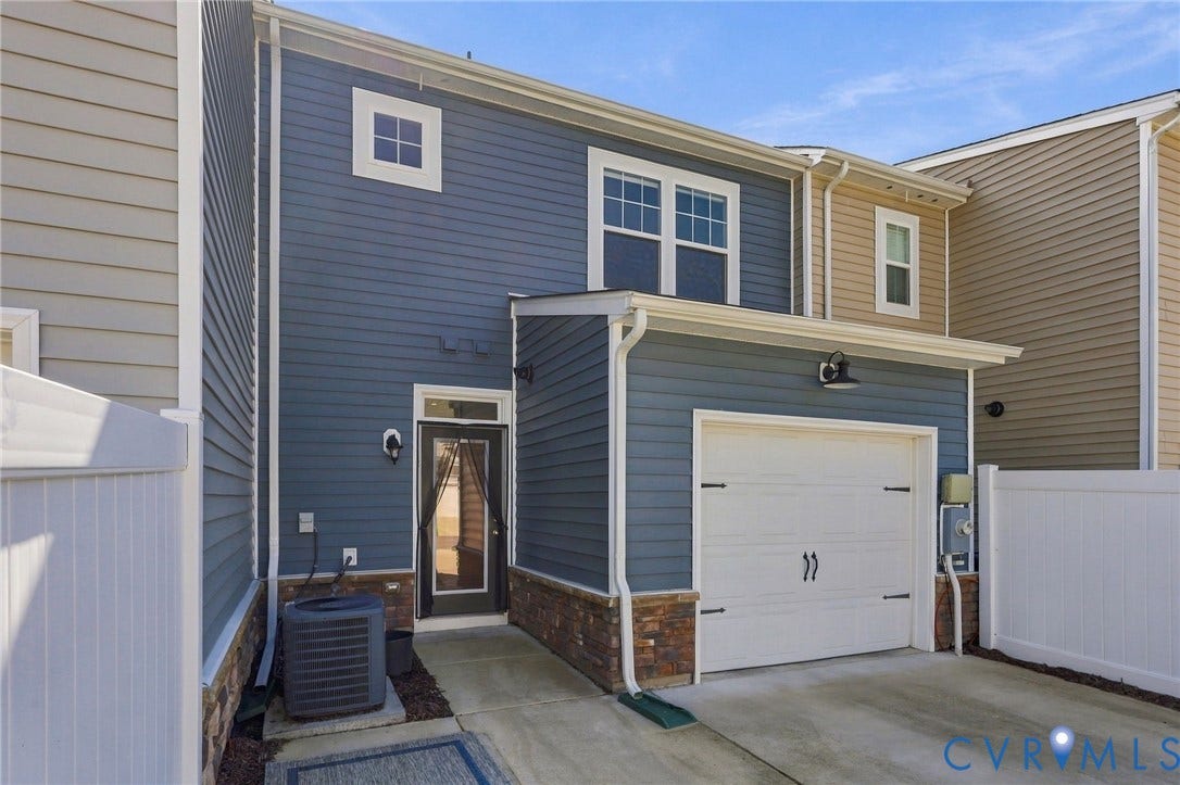 10818 Ashton Poole Place, Henrico, VA 23059 Exterior featuring blue and tan siding, white garage door, stone accents, and white fencing
