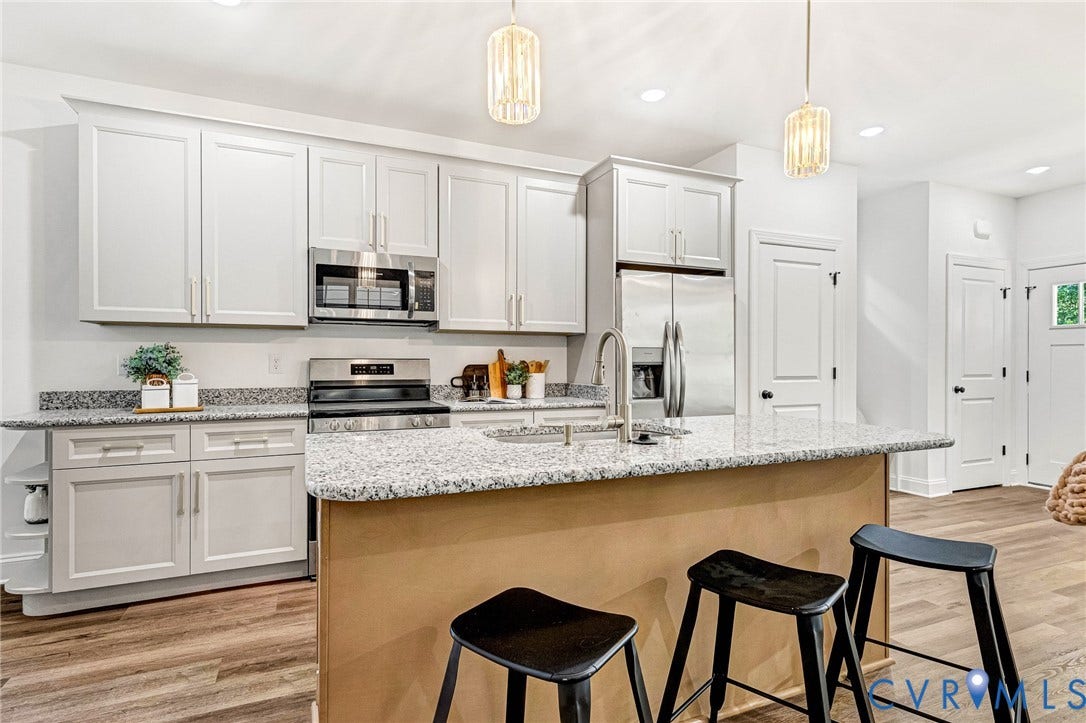 1807 Gordon Avenue, Oak Grove, Oak Grove, VA 23224 White cabinetry and granite countertops, stainless steel appliances, kitchen island with seating, and wood-finish flooring