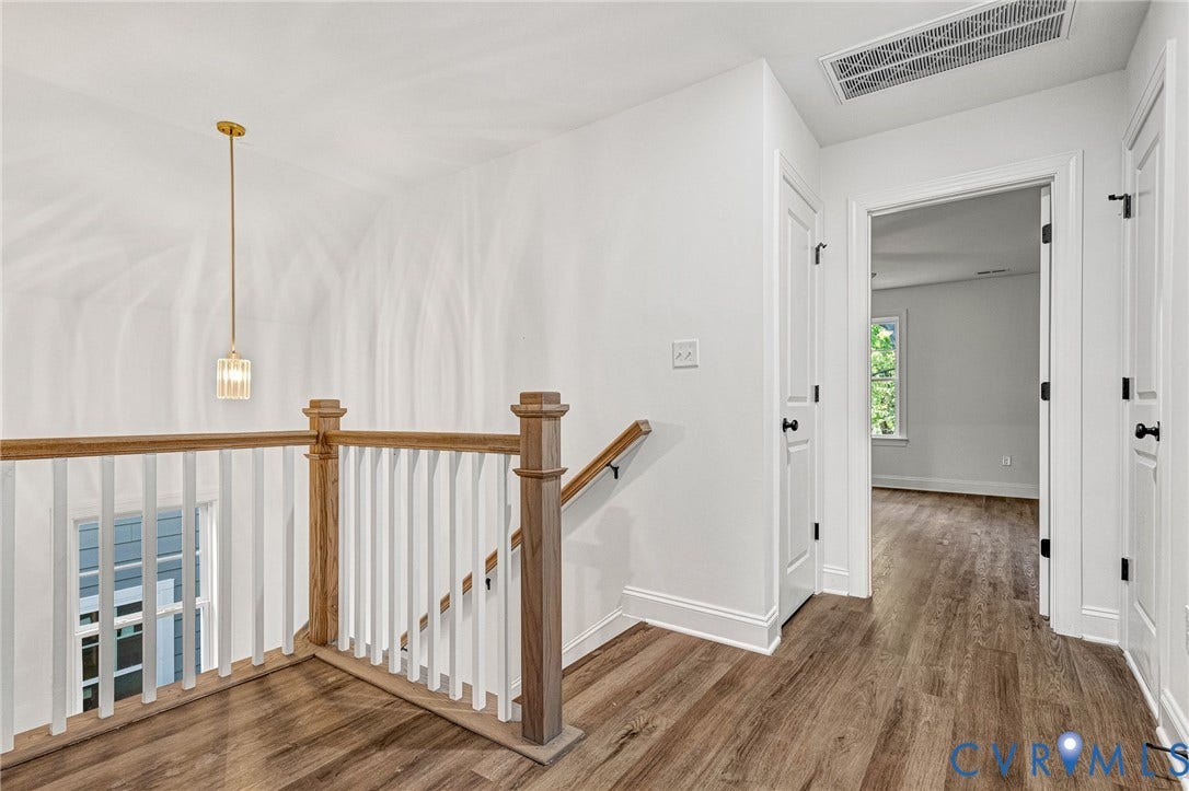 1807 Gordon Avenue, Oak Grove, Oak Grove, VA 23224 Wood-finish flooring throughout, white baluster railing with wood-finish handrail, contemporary pendant lighting, white interior doors, and black hardware
