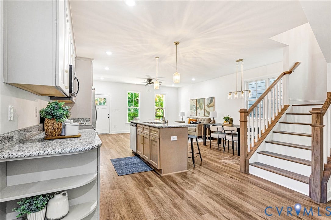 1807 Gordon Avenue, Oak Grove, Oak Grove, VA 23224 Open-concept living area featuring wood-finish flooring, a kitchen island with seating, pendant lighting, and a staircase with wood newel posts