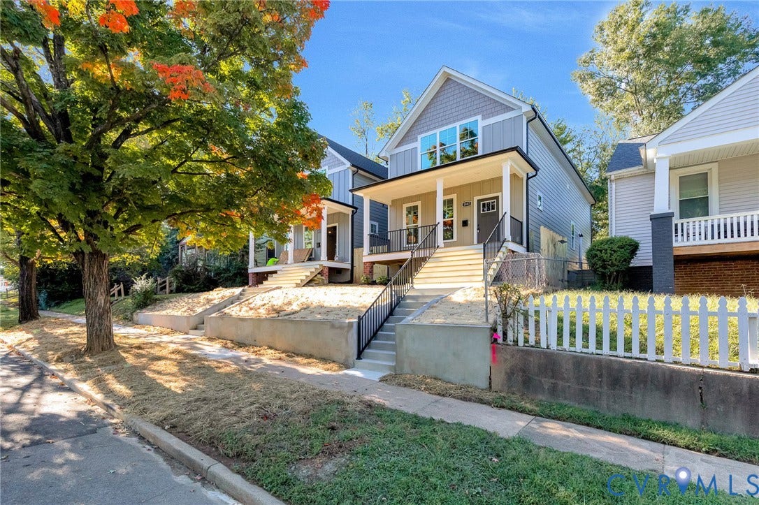 1807 Gordon Avenue, Oak Grove, Oak Grove, VA 23224 Modern facade with gray siding and shingle accents, covered front porch with white columns, concrete steps with black railings, and a partial white picket fence