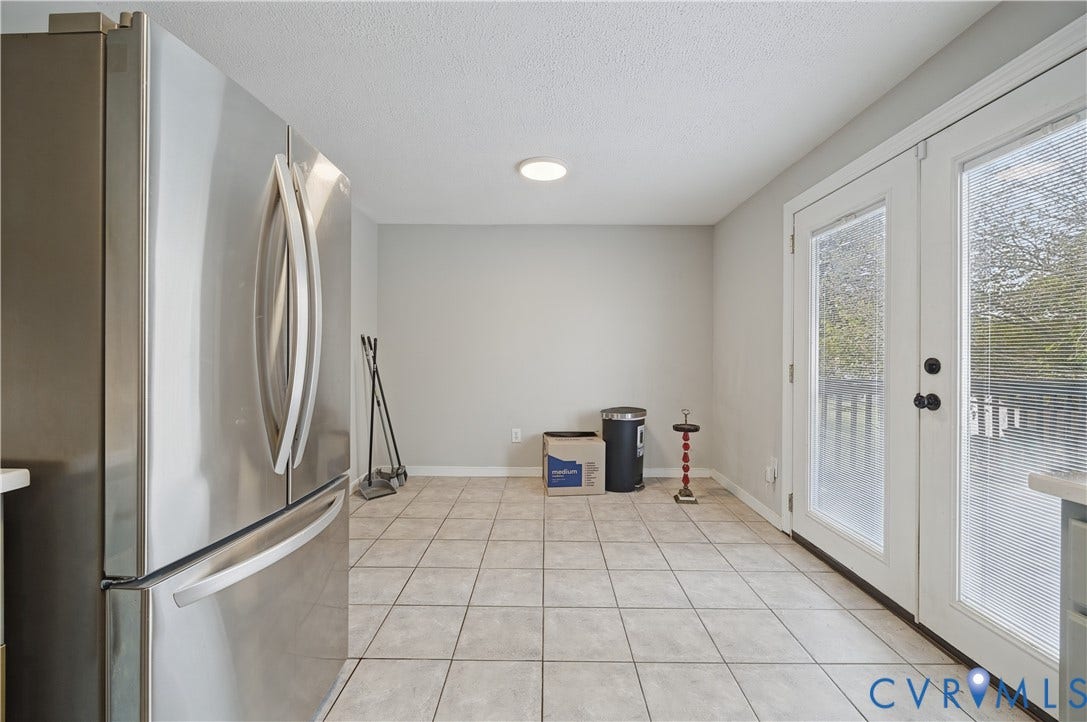 Stainless steel refrigerator, recessed ceiling lighting, light gray wall paint, tiled flooring, and double glass-paneled doors
