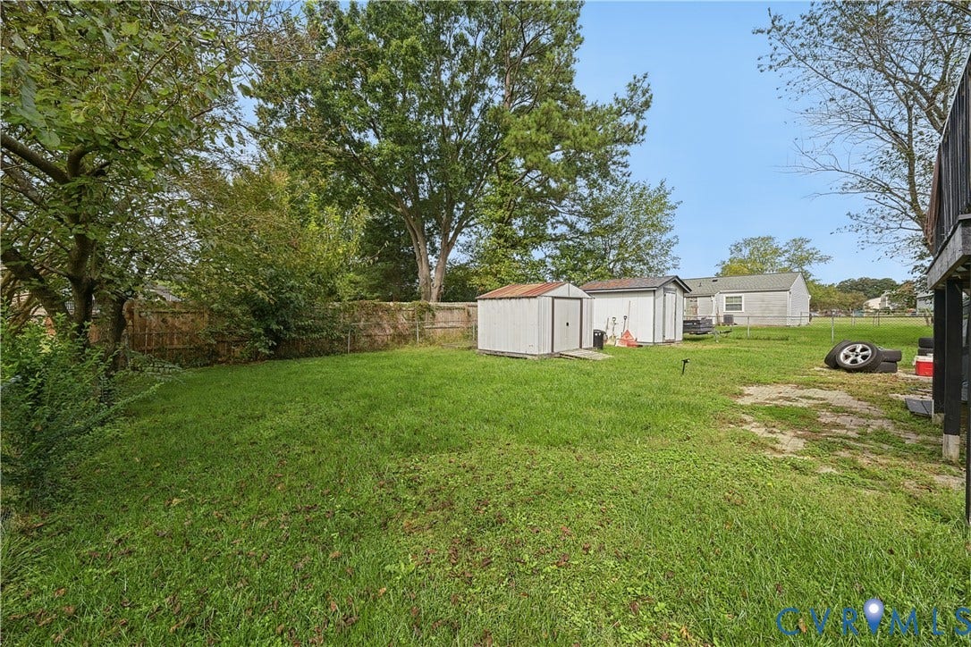 Expansive green space with mature trees and multiple storage sheds