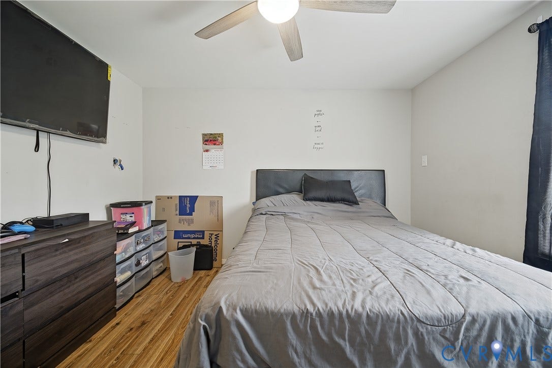 Wood-finish flooring with a ceiling fan and a wall-mounted television