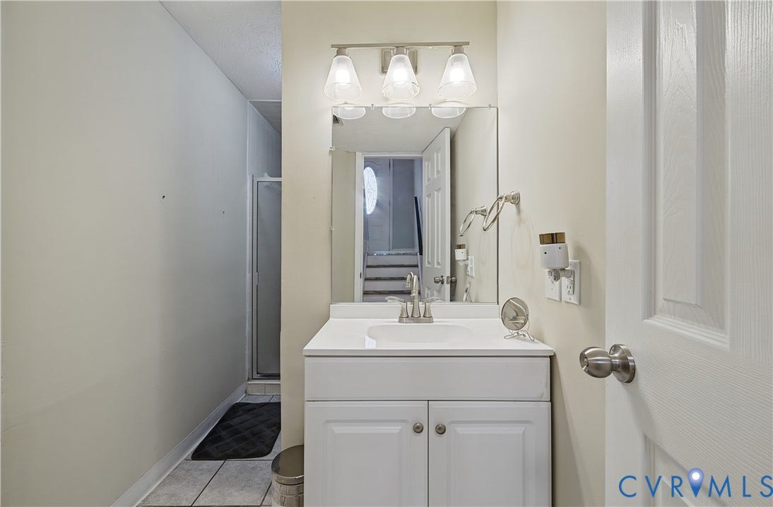 White vanity with integrated sink, chrome faucet, and overhead three-light fixture