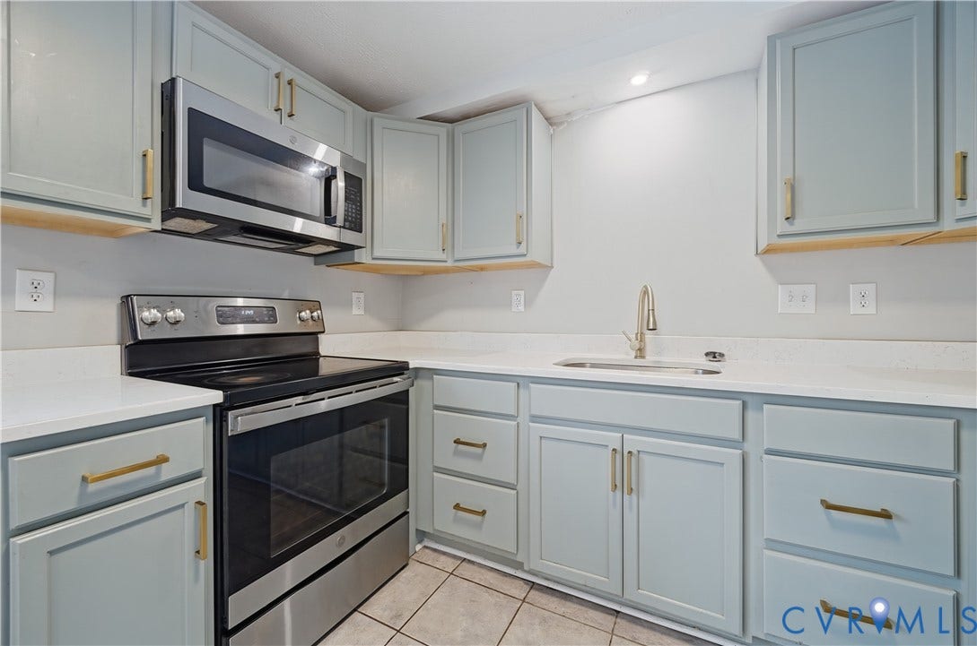 Updated kitchen featuring light-toned cabinetry, light-colored countertops, stainless steel appliances, and tile flooring