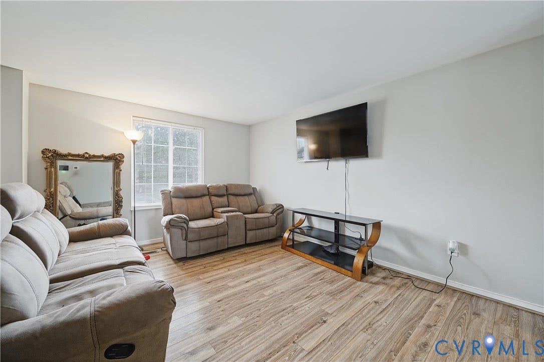 Light gray wall paint, wood-finish flooring, and a single window with white trim