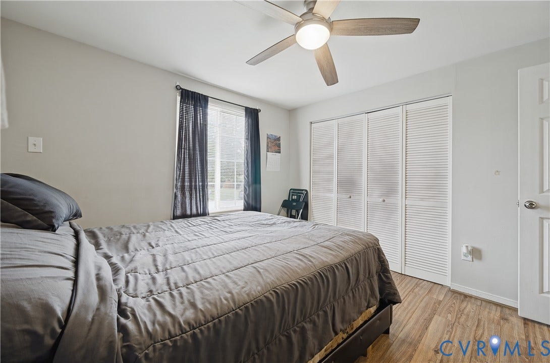 Wood-finish flooring, ceiling fan with integrated lighting, window with a white frame, and bi-fold louvered closet doors