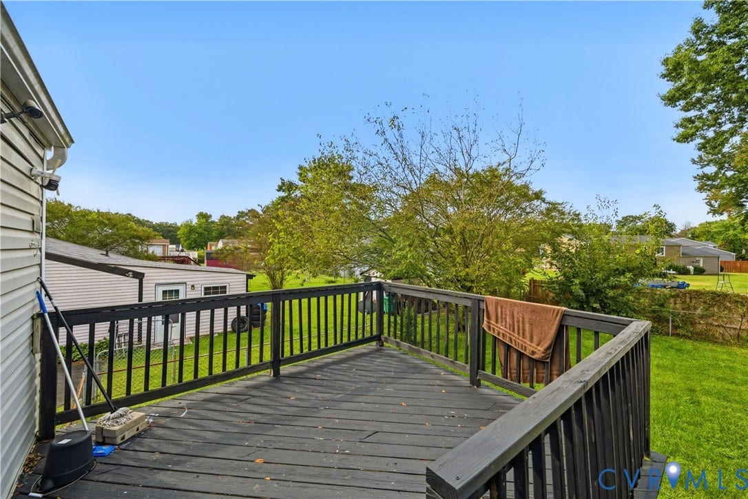 Outdoor deck with wood railings, overlooking a grassy yard area