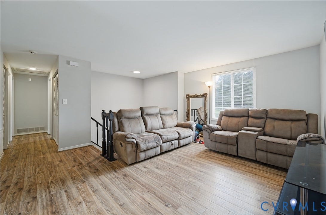Wood-finish flooring throughout, light gray wall finishes, recessed ceiling lighting, and a white-framed window