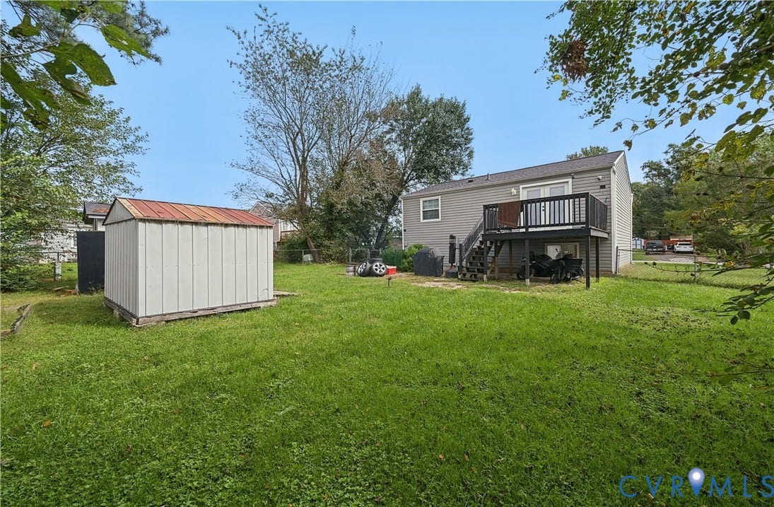 Expansive grass lawn with a storage shed featuring a metal roof