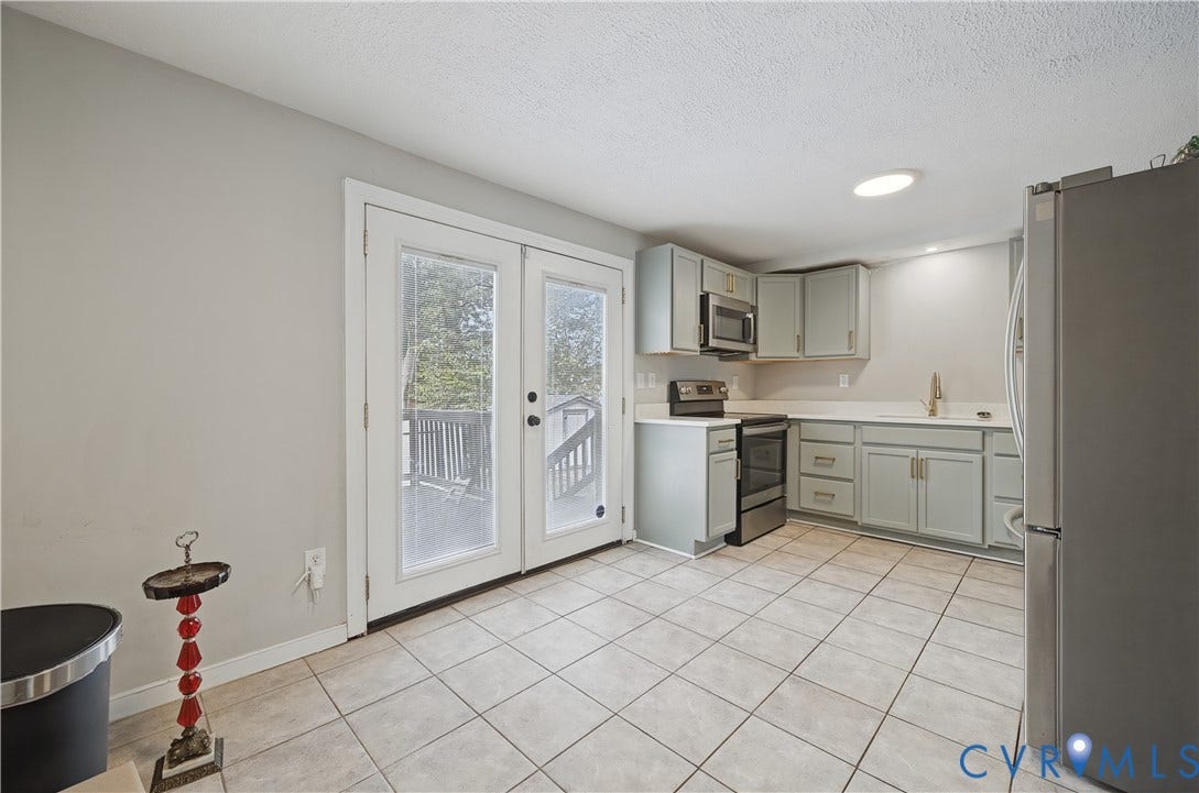 Contemporary kitchen with light-toned cabinetry, stainless steel appliances, solid surface countertops, and tile flooring