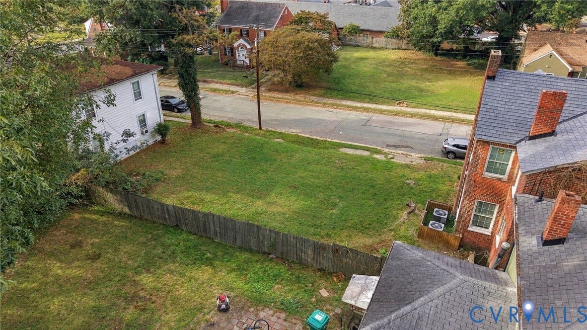 Expansive lot featuring a wooden privacy fence, mature trees, and a manicured lawn