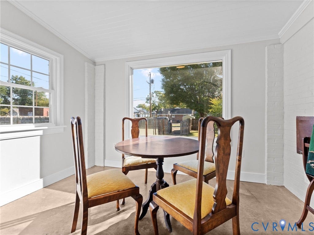 Light-filled room featuring multiple windows, crown molding, and a painted brick accent wall