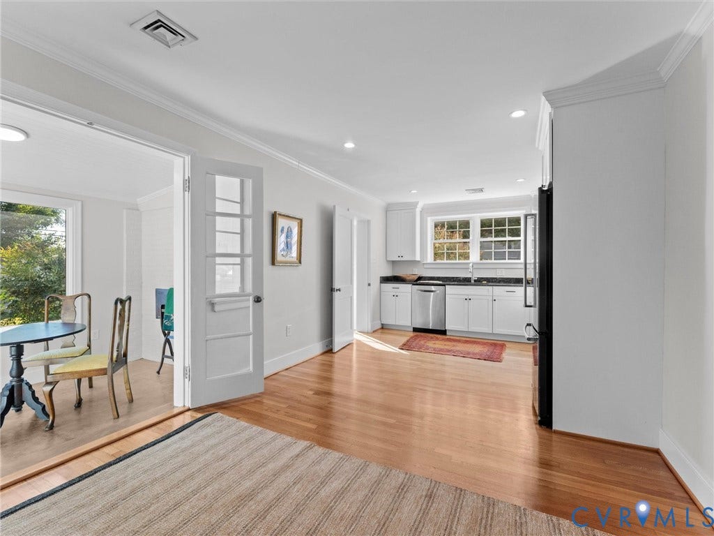 Kitchen featuring white cabinetry, dark countertops, stainless steel dishwasher, and wood-finish flooring