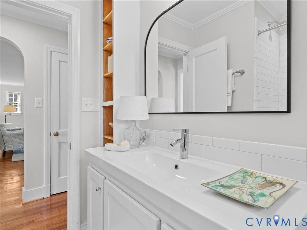 White vanity with integrated sink, chrome faucet, subway tile backsplash, and a large framed mirror
