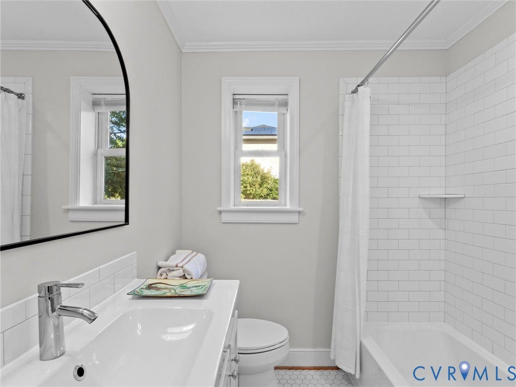Modern bathroom featuring a single vanity, undermount sink, chrome faucet, white subway tile shower surround, and hexagonal floor tiles