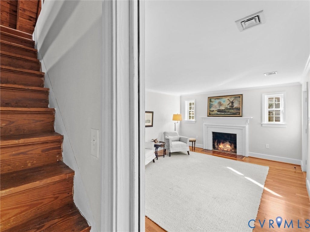 Living area featuring wood-finish flooring, a white mantel, and multiple windows