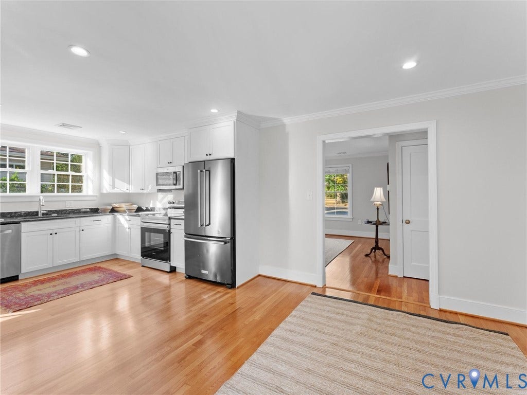 Kitchen featuring stainless steel appliances, white cabinetry, dark countertops, recessed lighting, and wood-finish flooring