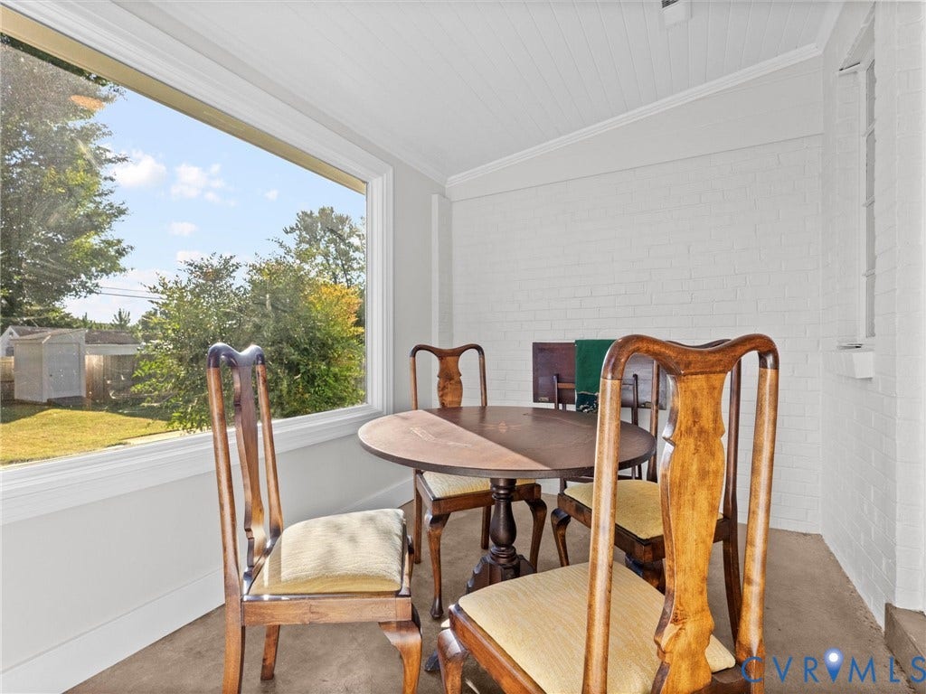 Expansive window with a deep sill, white-painted brick wall, and a sloped planked ceiling