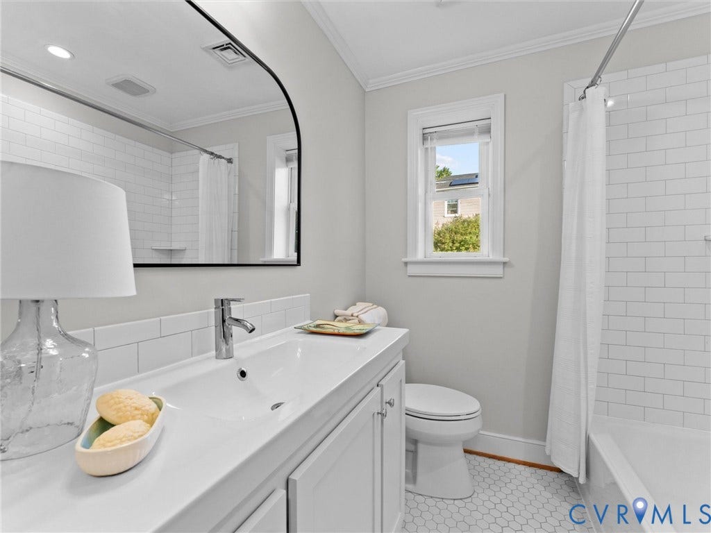 Modern bathroom featuring a single vanity with an integrated sink, chrome faucet, a tub with subway tile surround, and hexagonal floor tiling